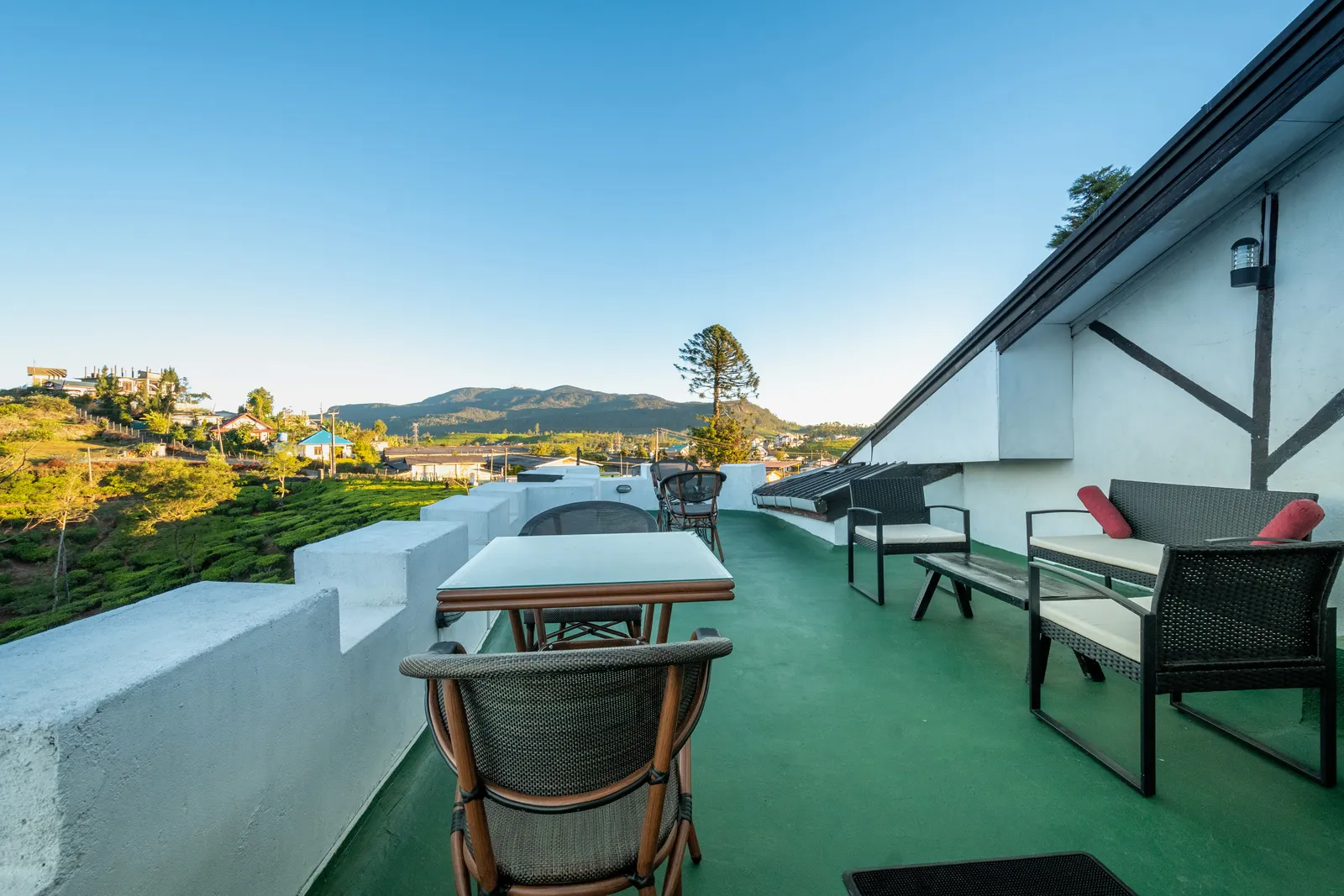 The upper terrace with wicker chairs and a view across the valley to the hills