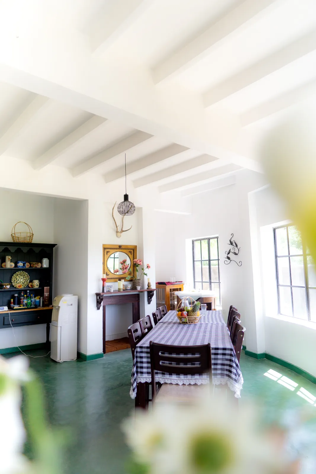 The dining room: a checked tablecloth on the table, a white beamed ceiling and a window to the garden