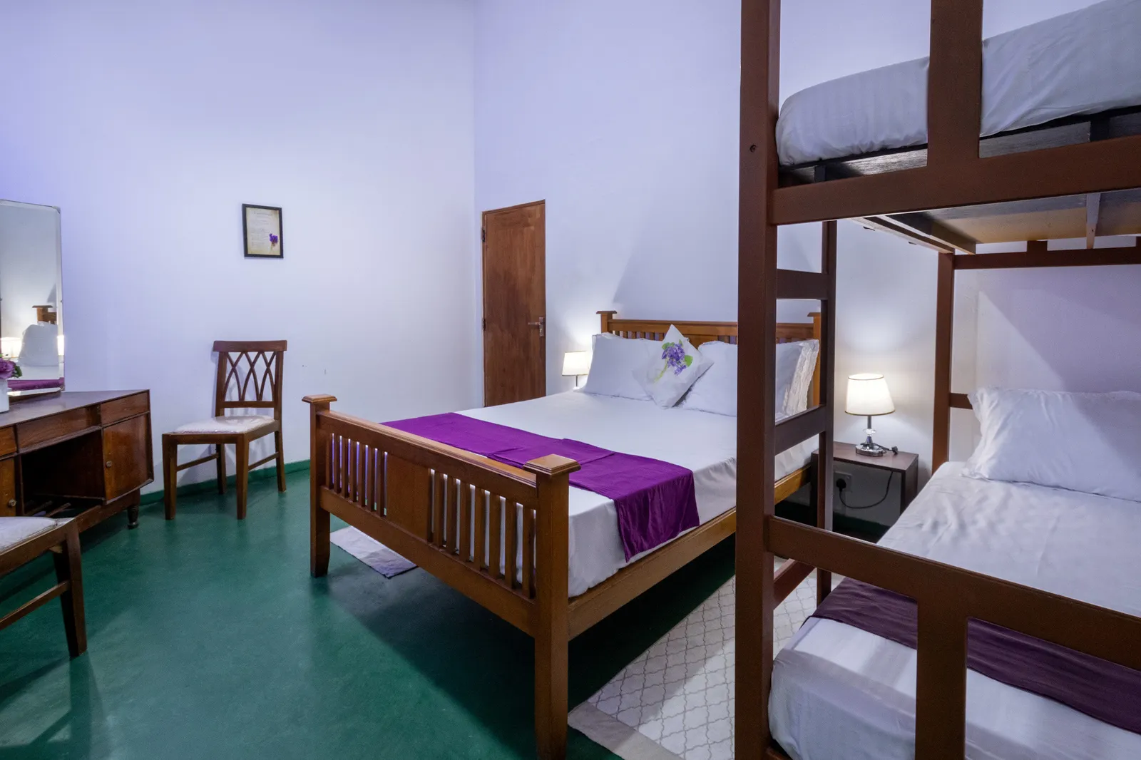 Violet bedroom: a double bed with a purple runner, a bunk bed and a dressing table on the green floor
