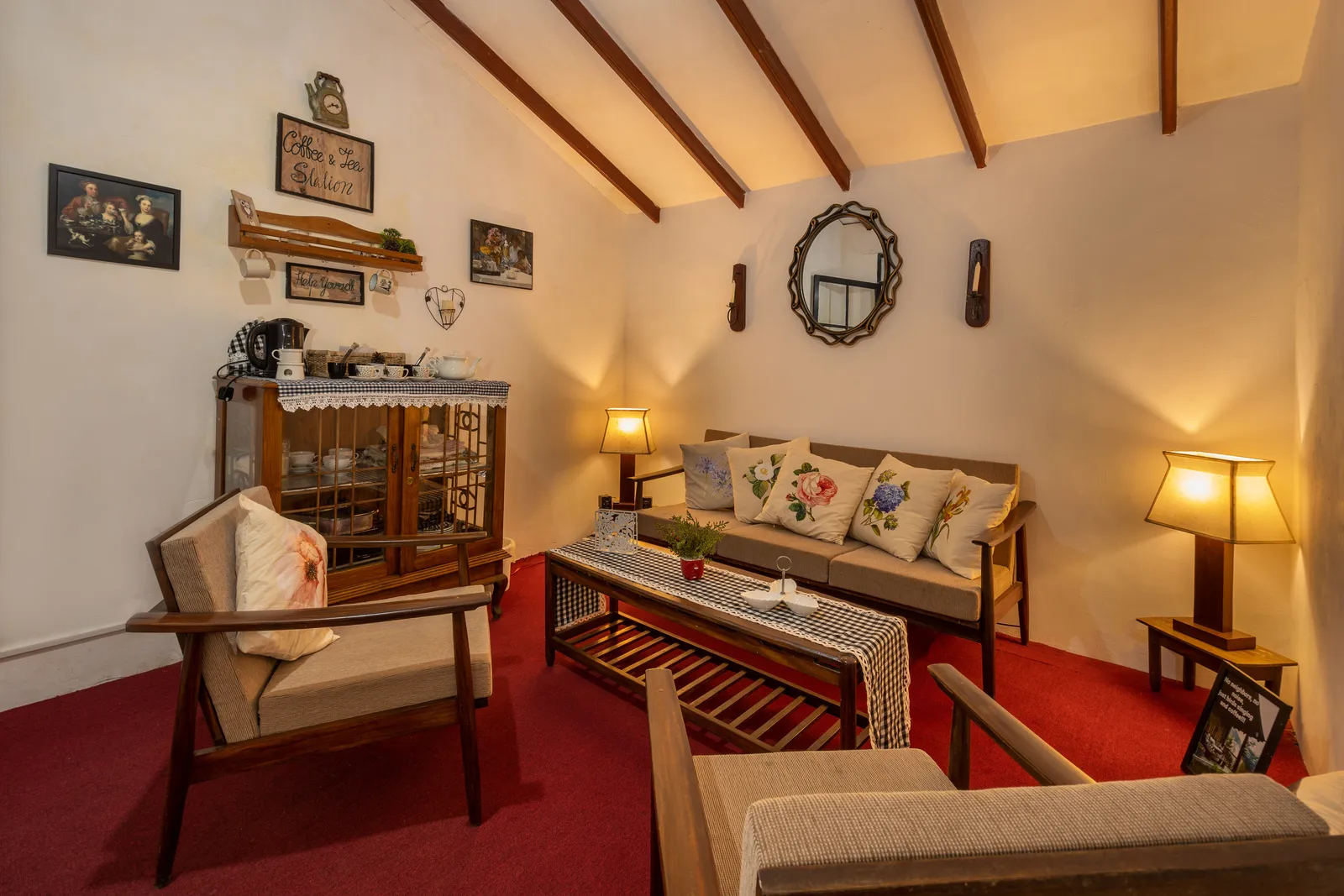 The tea station and sitting area, with a glass-fronted cabinet, lamps and armchairs on a red floor